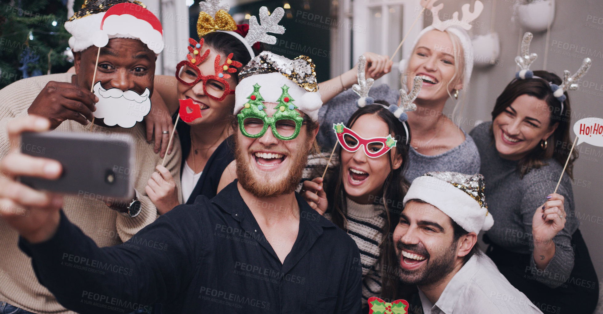 Buy stock photo Christmas, party and friends taking a selfie on a phone together with goofy, funny and silly props. Diversity, festive and happy people taking picture on a smartphone at festive xmas event at a home.