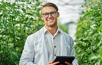 Buy stock photo Portrait of a handsome young scientist using a digital tablet while studying plants and crops outdoors on a farm