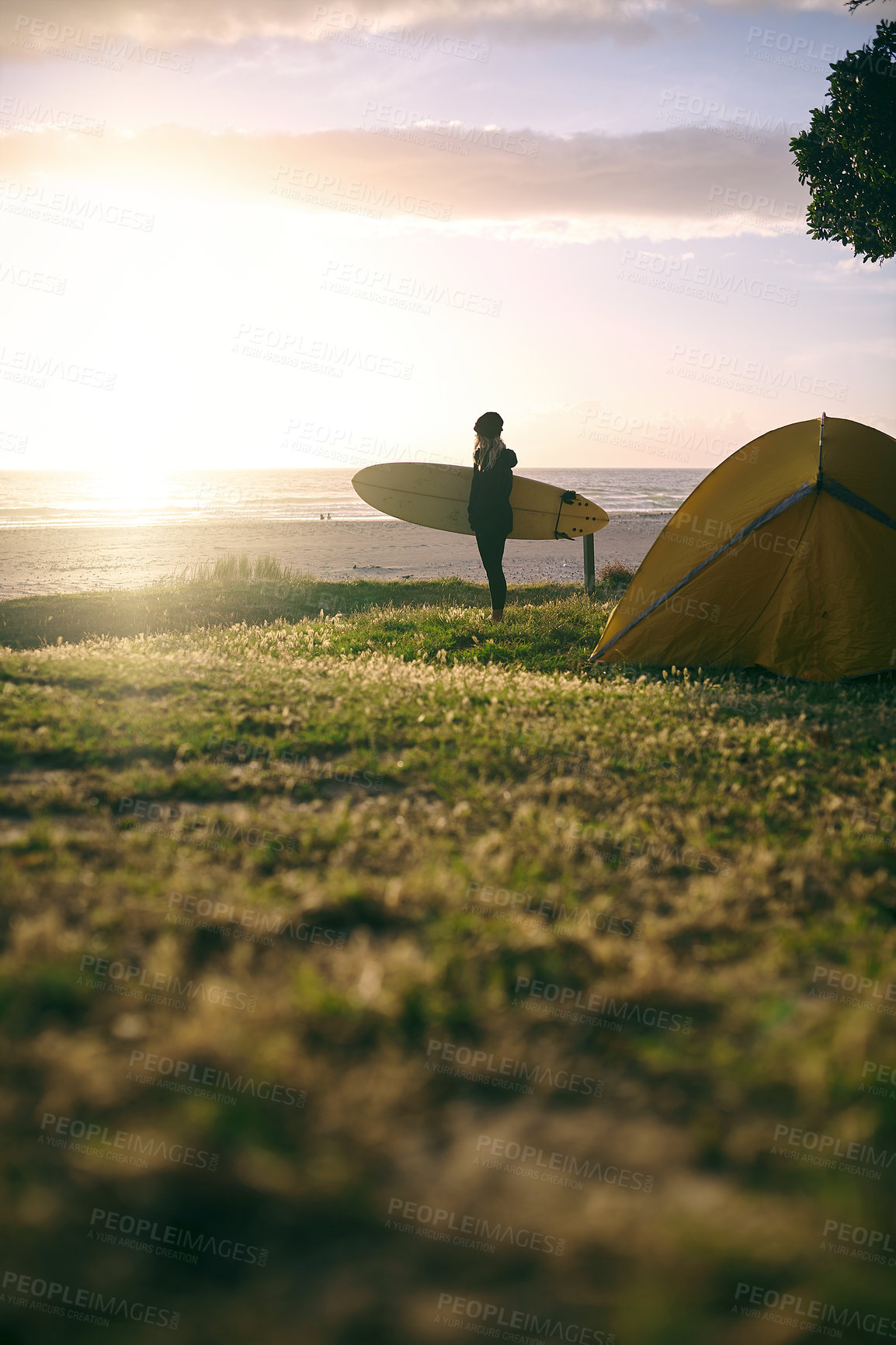 Buy stock photo Camping, surfer and woman at beach at sunset for travel, thinking or girl on trip in nature for adventure. Tent, surfboard and outdoor at sea for holiday, vacation and sports hobby on tropical island