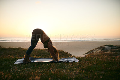 Buy stock photo Full length shot of an unrecognizable woman holding a downward facing dog position during a yoga session outdoors