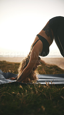 Buy stock photo Cropped shot of an attractive young woman holding a downward facing dog position during a yoga session outdoors