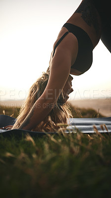 Buy stock photo Cropped shot of an attractive young woman holding a downward facing dog position during a yoga session outdoors