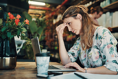 Buy stock photo Cropped shot of an attractive young businesswoman sitting alone in her floristry and feeling stressed while using her laptop