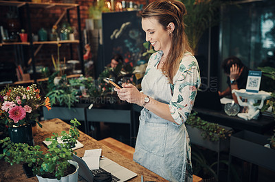 Buy stock photo Cropped shot of an attractive young businesswoman standing in her floristry and using her cellphone to photograph her flowers