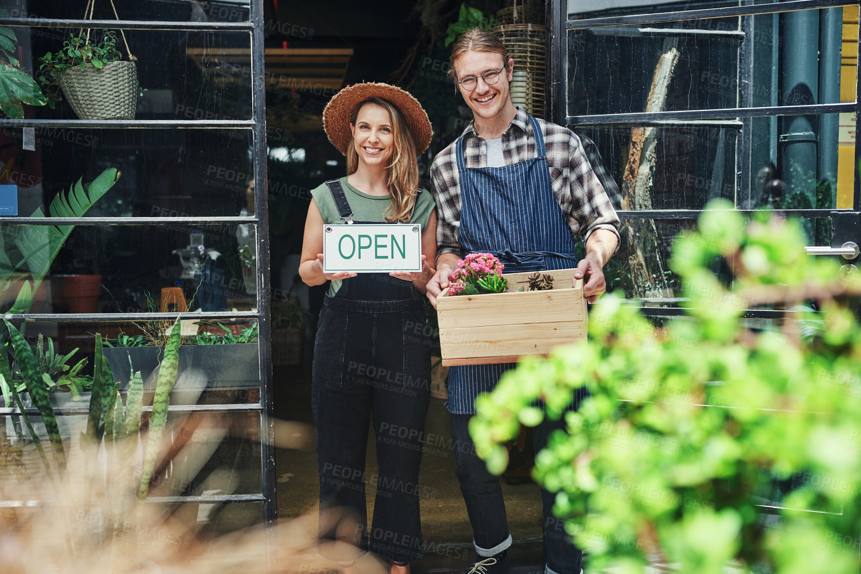 Buy stock photo Cropped portrait of two young business owners standing at the entrance of their floristry together and holding potting supplies