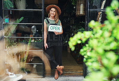Buy stock photo Full length portrait of an attractive young business owner standing alone and holding the open sign at the floristry entrance