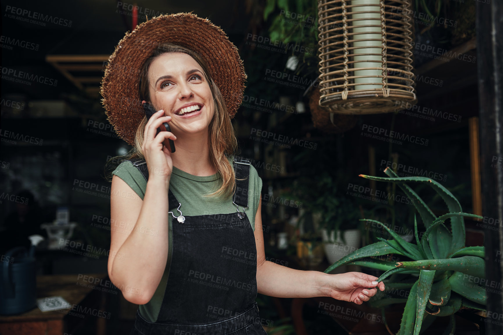 Buy stock photo Cropped shot of an attractive young business owner standing alone at the entrance of her floristry while on a phonecall