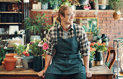 Buy stock photo Cropped shot of a handsome young businessman sitting alone in his flower shop during the day