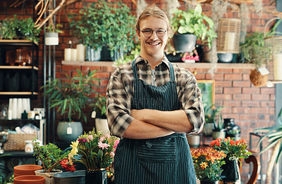 Buy stock photo Cropped portrait of a handsome young business owner standing in his floristry alone with his arms folded
