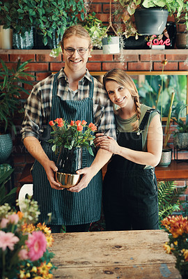 Buy stock photo Cropped portrait of two young business owners standing in their floristry together while holding a bouquet of roses