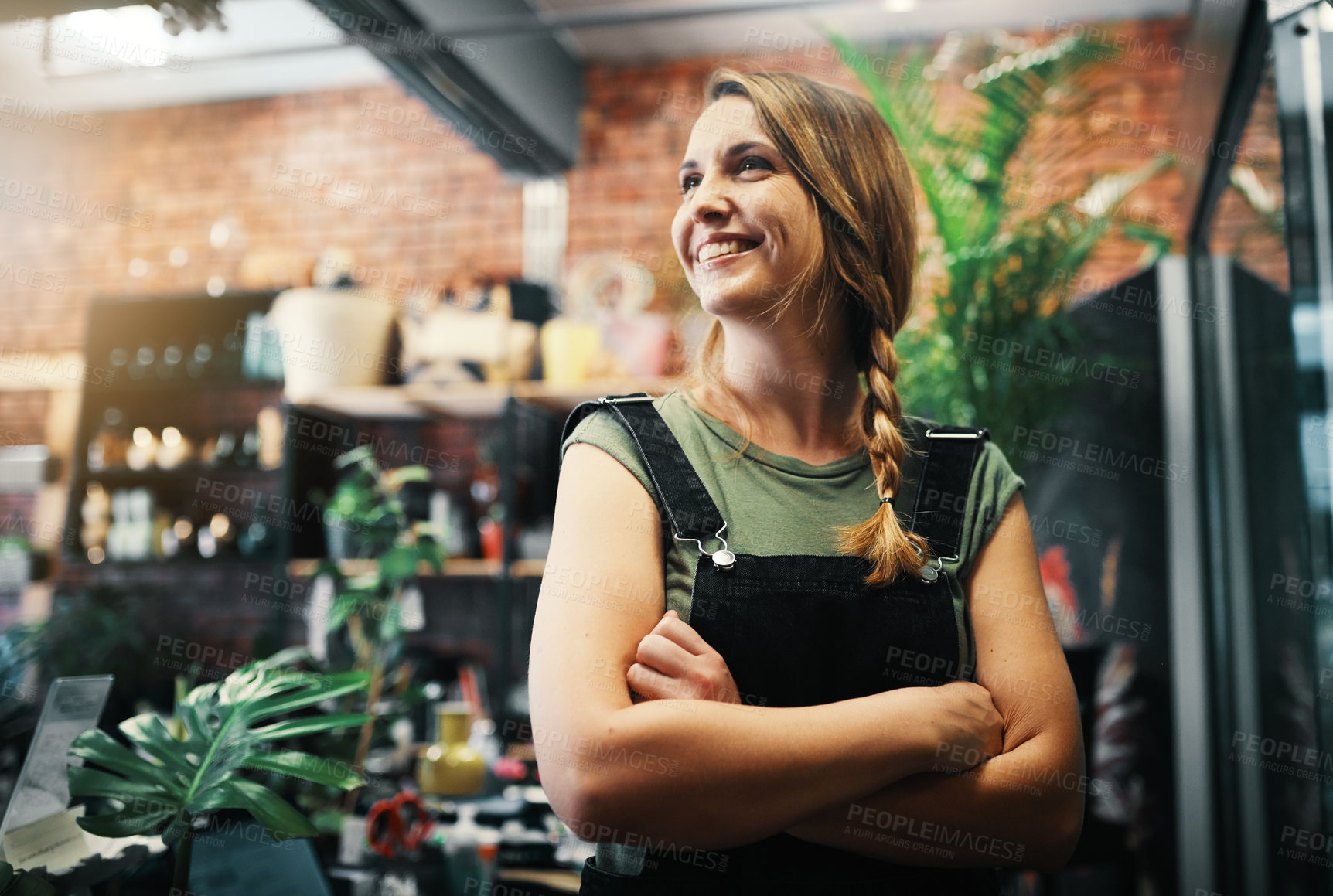 Buy stock photo Cropped shot of an attractive young business owner standing in her floristry alone with her arms folded