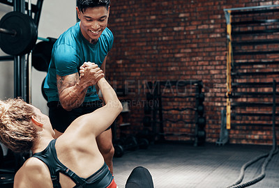 Buy stock photo Cropped shot of a handsome young sportsman assisting his gym partner to get up in a gym