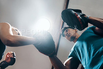 Buy stock photo Low angle shot of a handsome young male fitness instructor coaching a female boxer in a gym