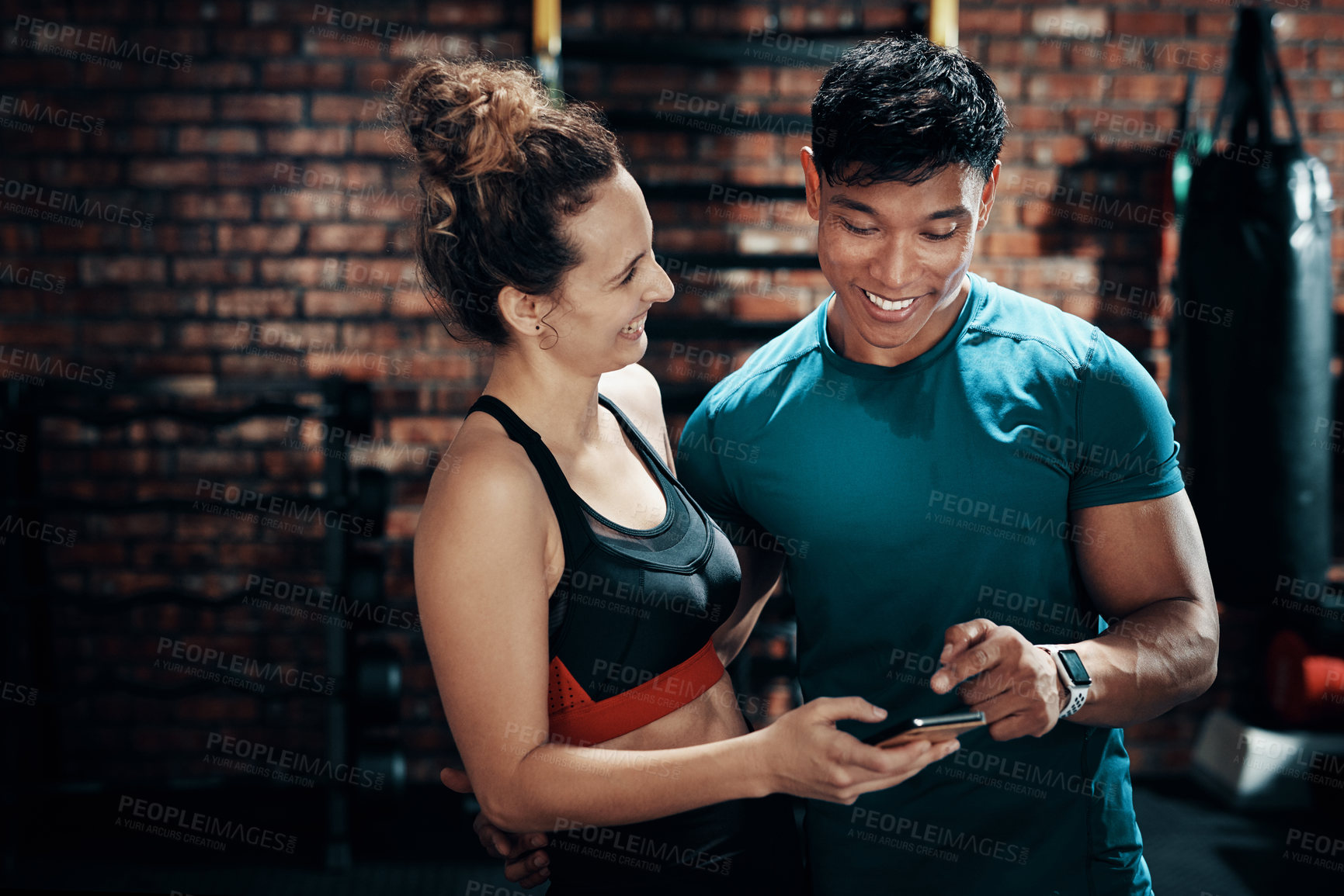 Buy stock photo Cropped shot of two young sportspeople using a smartphone together in a gym