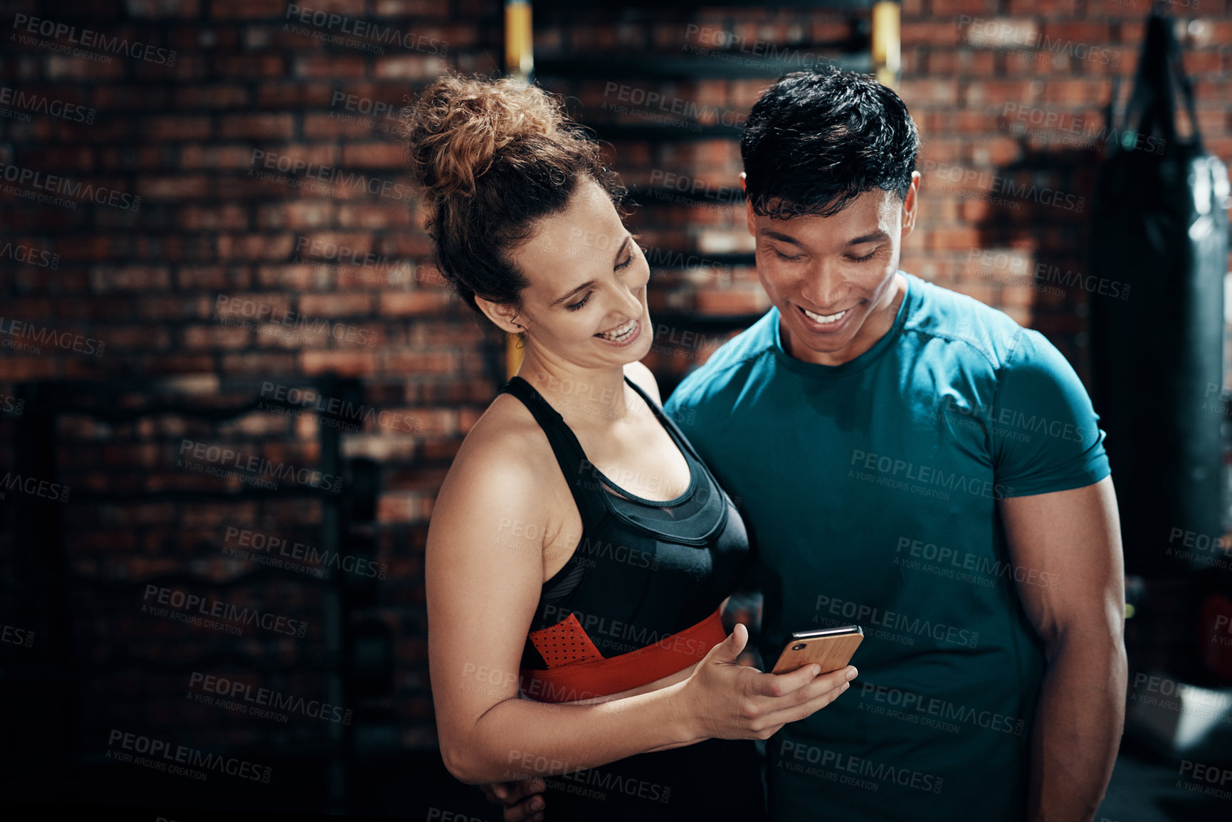 Buy stock photo Cropped shot of two young sportspeople using a smartphone together in a gym