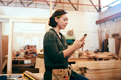 Buy stock photo Cropped shot of a female carpenter using her cellphone in her workshop