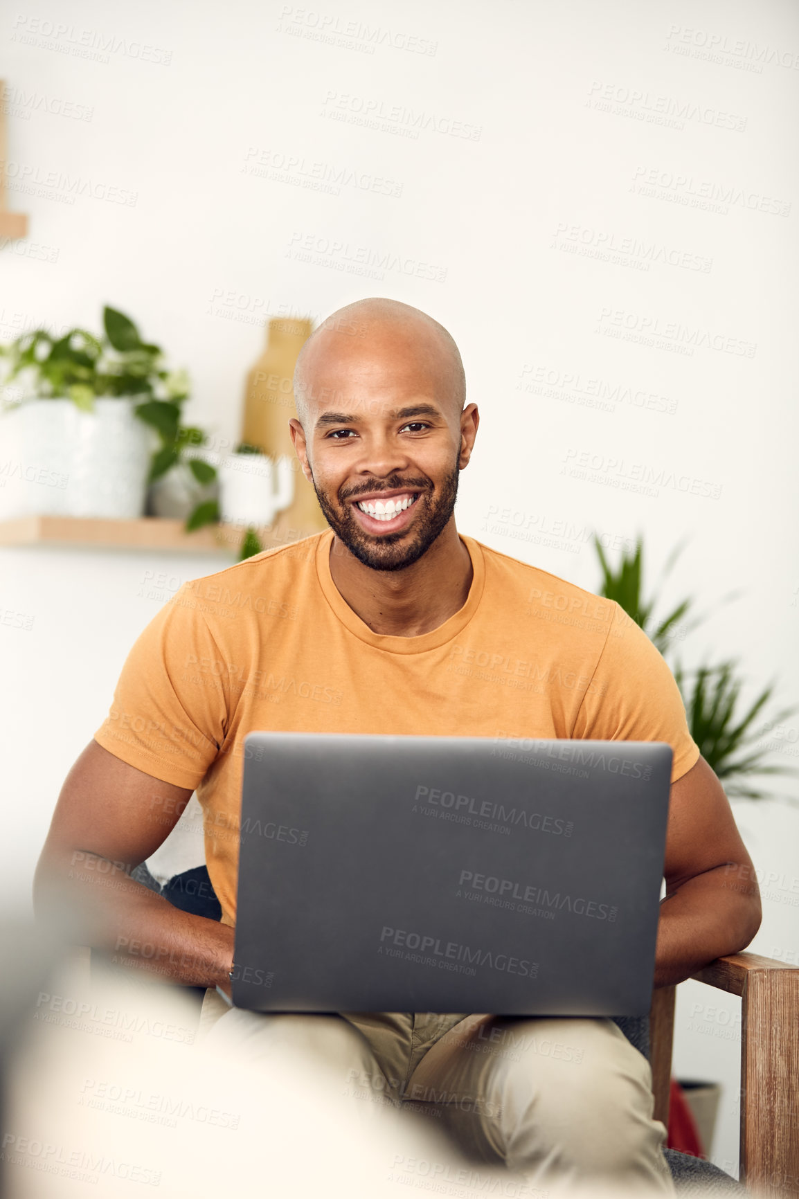 Buy stock photo Shot of a young man using his laptop while sitting on the sofa at home