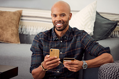 Buy stock photo Cropped shot of a young man using his credit card while using his cellphone