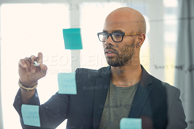 Buy stock photo Cropped shot of a young businessman brainstorming with notes on a glass wall in an office