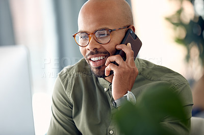 Buy stock photo Cropped shot of a young businessman talking on his cellphone while sitting behind his computer