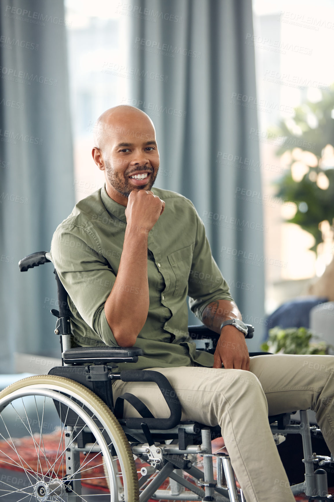 Buy stock photo Cropped shot of a young man sitting in his wheelchair at home
