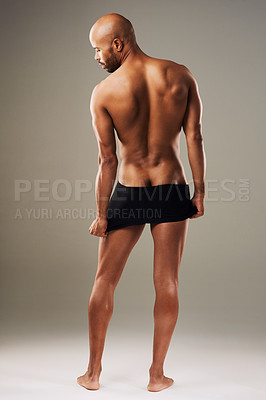 Buy stock photo Rearview shot of a handsome young man posing in underwear against a grey background