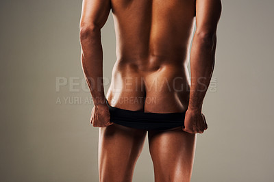 Buy stock photo Rearview shot of an unrecognizable young man posing in underwear against a grey background