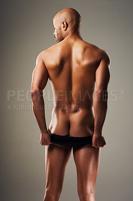 Buy stock photo Rearview shot of a handsome young man posing in underwear against a grey background