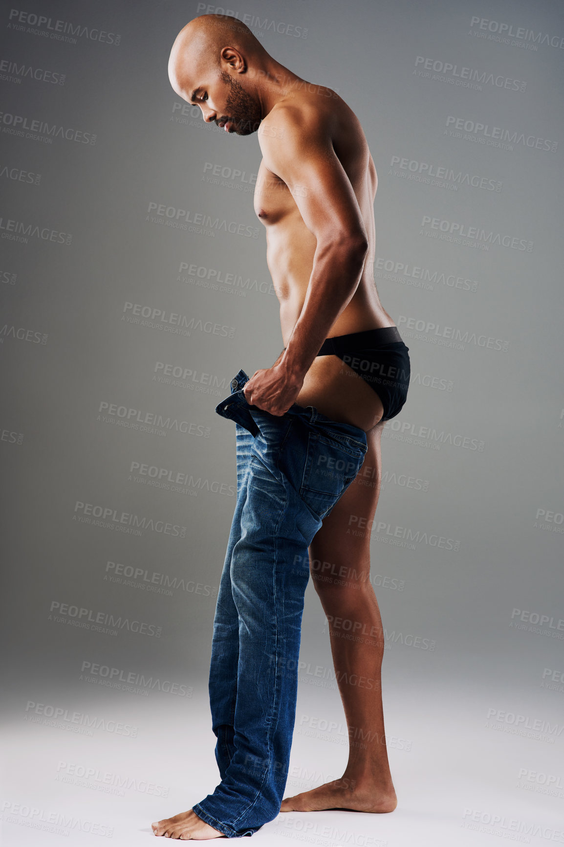Buy stock photo Full length shot of a handsome young man undressing against a grey background