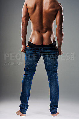 Buy stock photo Rearview shot of an unrecognizable young man undressing against a grey background