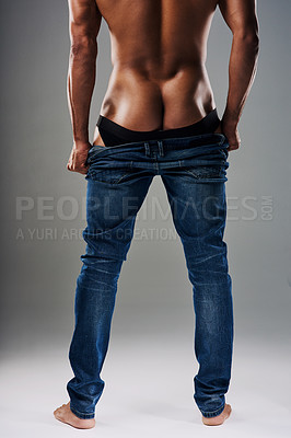 Buy stock photo Rearview shot of an unrecognizable young man undressing against a grey background