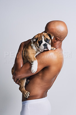 Buy stock photo Shot of a handsome young man posing with his adorable puppy against a grey background