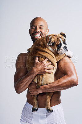 Buy stock photo Portrait of a handsome young man posing with his adorable puppy against a grey background