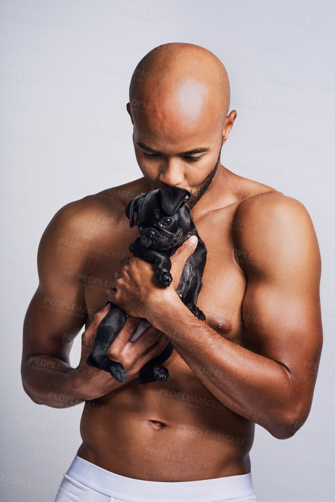 Buy stock photo Shot of a handsome young man posing with his adorable puppy against a grey background