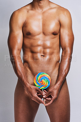 Buy stock photo Cropped shot of an unrecognizable naked man posing with a giant lollipop covering his genital area against a grey background