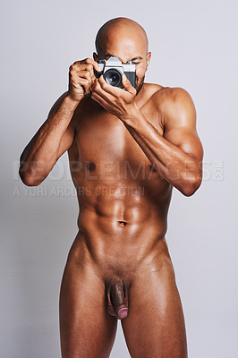 Buy stock photo Shot of a naked young man taking pictures with a camera against a grey background