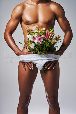 Buy stock photo Cropped shot of an unrecognizable man posing with a bouquet of flowers stuffed in his underwear against a grey background