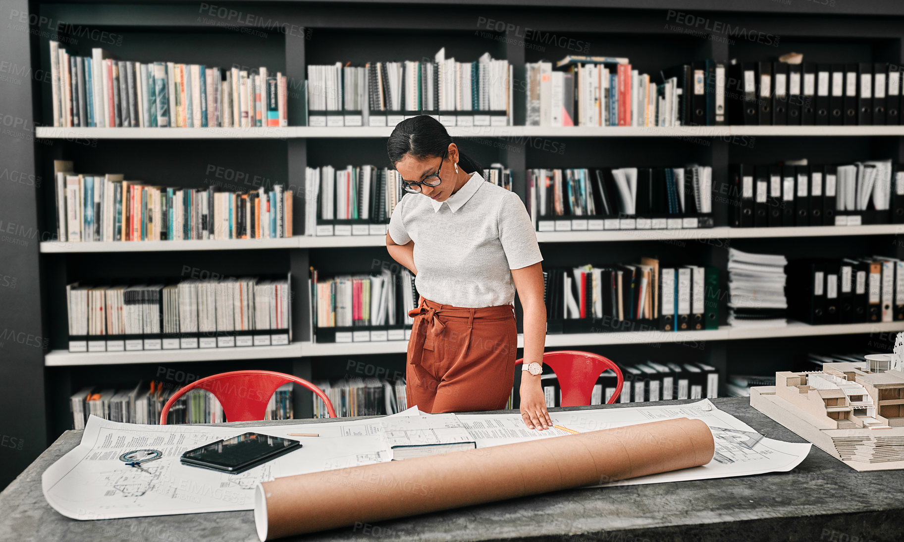 Buy stock photo Cropped shot of an attractive young female architect working with blueprints in a modern office