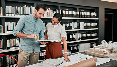 Buy stock photo Cropped shot of two aspiring young architects looking at a notebook working together in a modern office