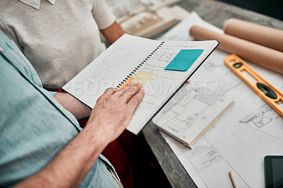 Buy stock photo Cropped shot of two unrecognizable architects looking at a notebook while working together in a modern office