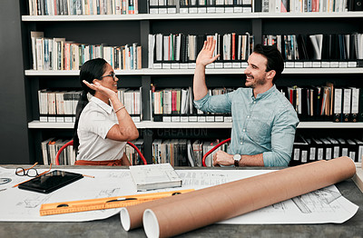 Buy stock photo Cropped shot of two cheerful young architects high fiving each other while working together in a modern office