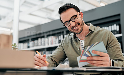 Buy stock photo Cropped shot of a handsome young male architect smiling while looking at a bunch of cards in a modern office