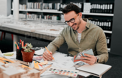 Buy stock photo Cropped shot of a handsome young male architect smiling while working with some blueprints in a modern office