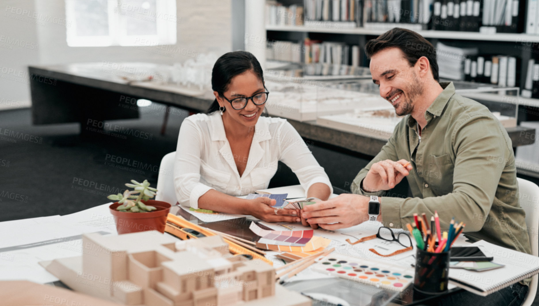 Buy stock photo Cropped shot of two aspiring young architects smiling while working together in a modern office