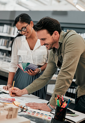 Buy stock photo Cropped shot of two aspiring young architects smiling while working together in a modern office