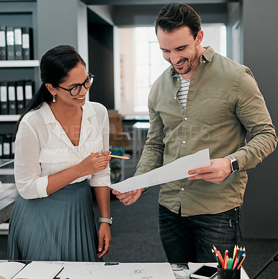 Buy stock photo Cropped shot of two aspiring young architects working with a blueprint in a modern office