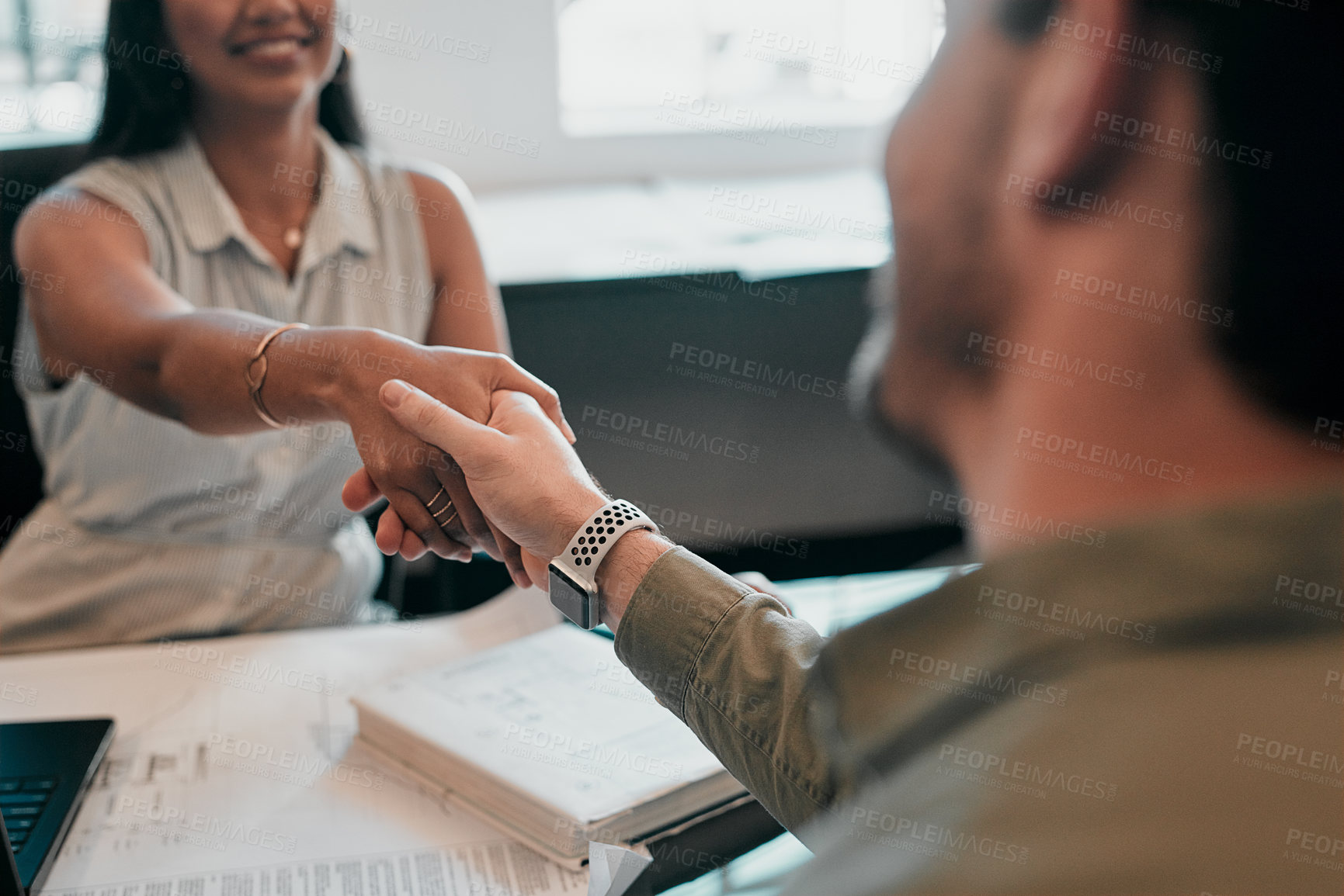 Buy stock photo Cropped shot of two young businesspeople shaking hands in an office