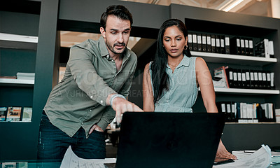 Buy stock photo Shot of two young businesspeople discussing something on a laptop