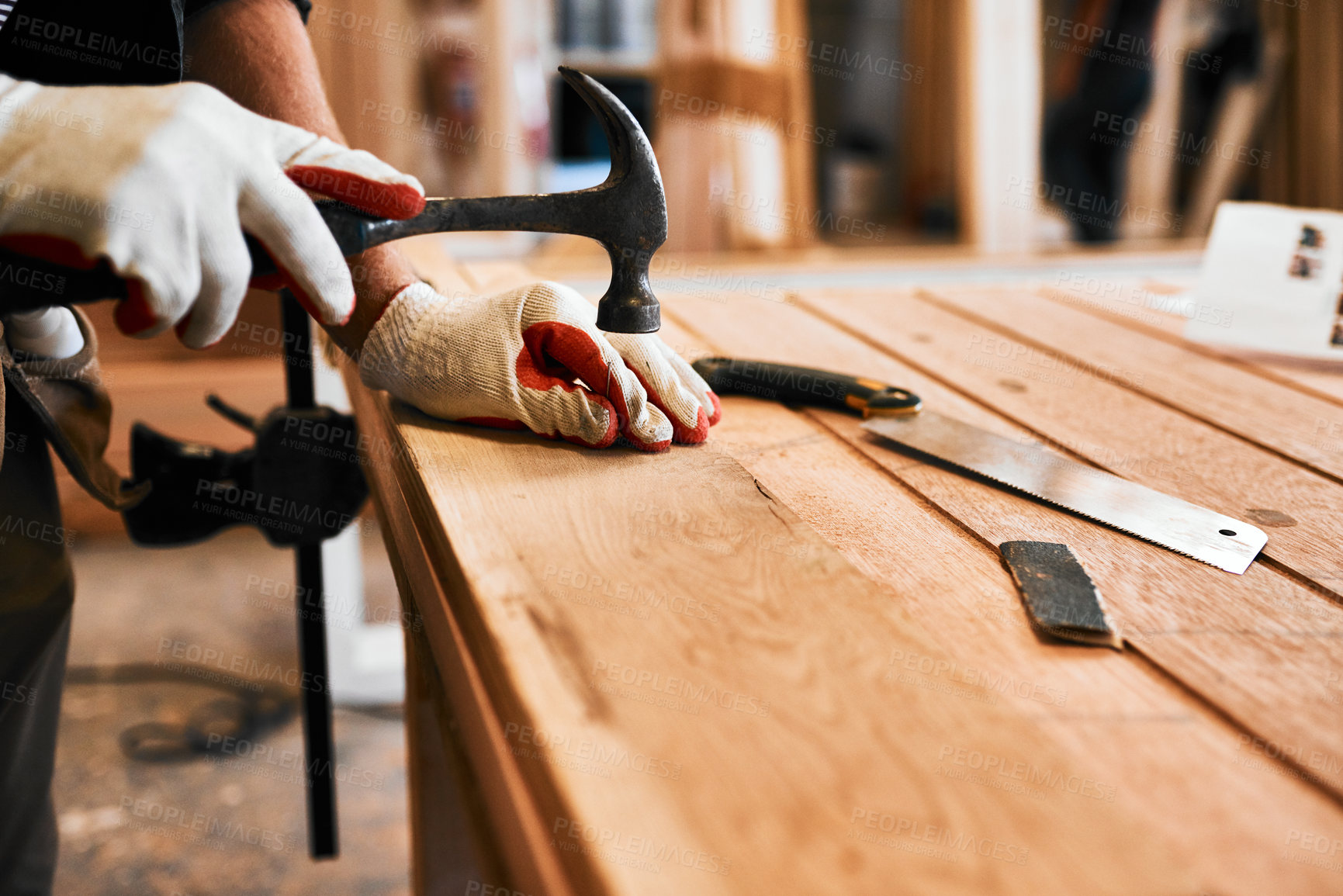 Buy stock photo Cropped shot of an unrecognizable carpenter hammering nails on wood inside a workshop