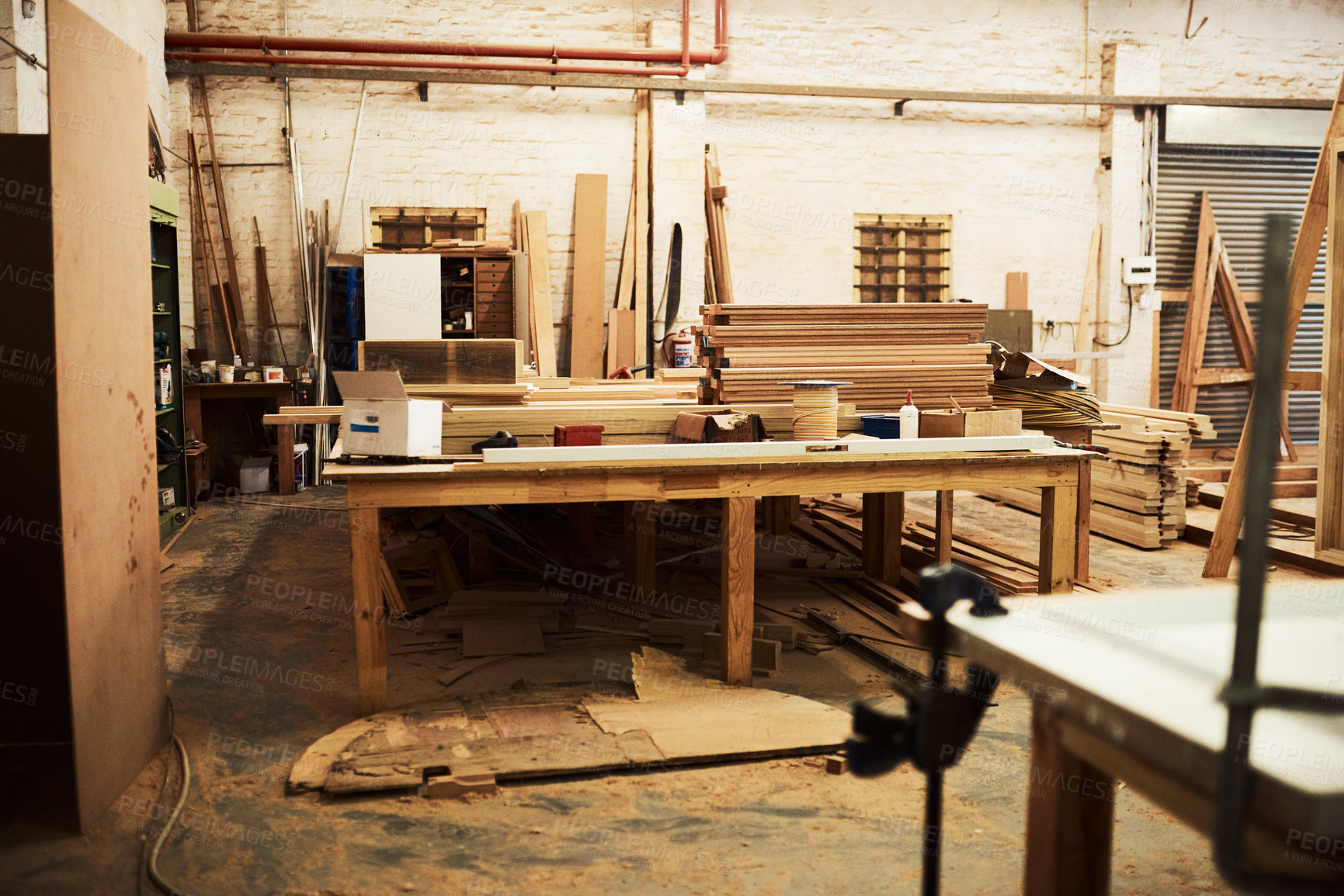 Buy stock photo Still life shot of work tables and piles of wood inside a carpentry workshop
